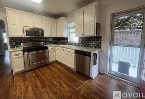 A kitchen with white cabinets and black countertops.
