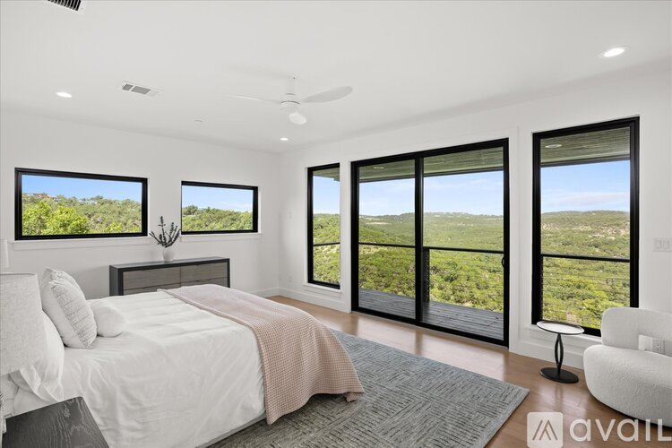 A bedroom with a large bed and a view of the outdoors through the windows.