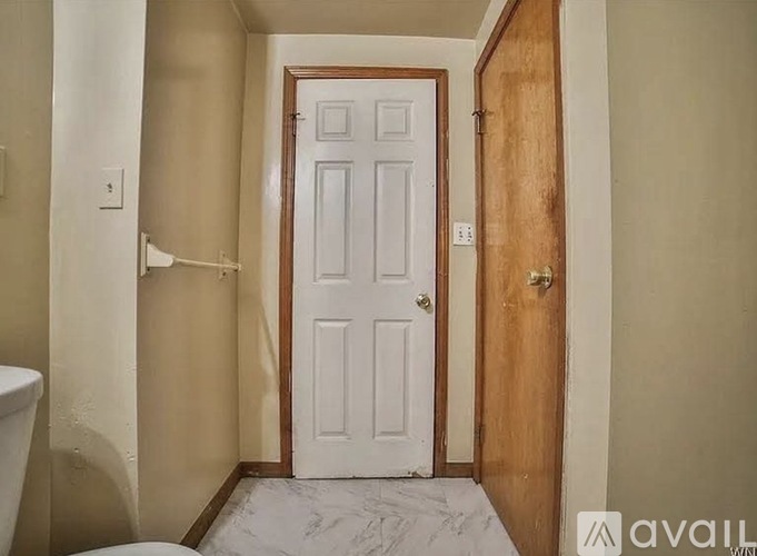 A white door is in a hallway with a wooden door on the right.