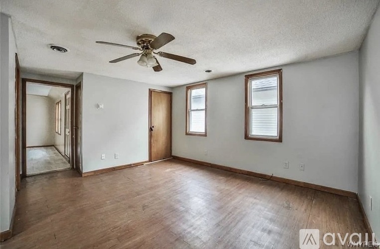 A room with a ceiling fan and wooden flooring.