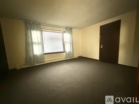 A room with a window and a door is available for rent.