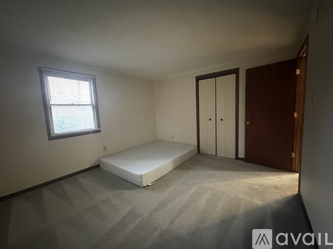 A bedroom with a bed, window, and two doors.