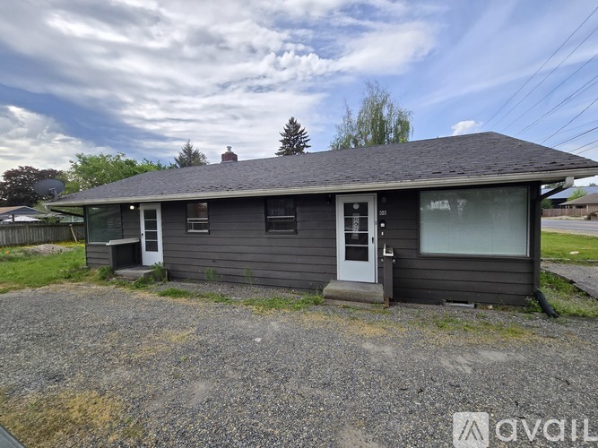 A small house with a gravel driveway in front.