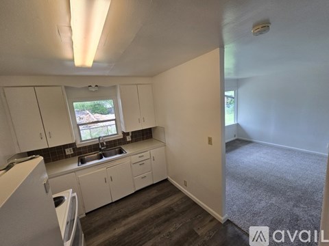 A kitchen with white cabinets and a window overlooking a road.