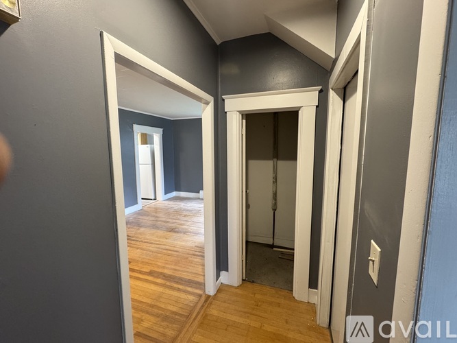 A hallway with a wooden floor and white trim.