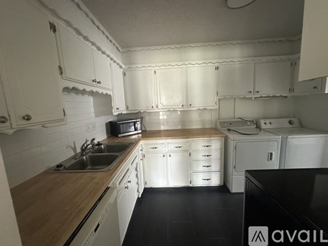 A kitchen with white cabinets and a wooden counter top.
