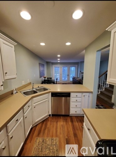 A kitchen with white cabinets and a wooden floor.