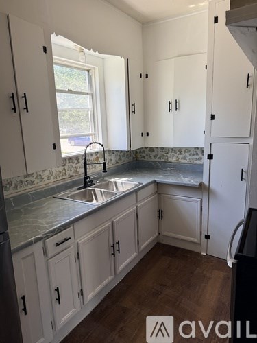 A kitchen with white cabinets and a marble countertop.