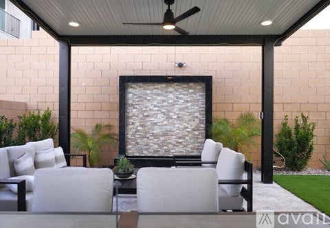 A patio with a couch, chairs, and a stone wall.