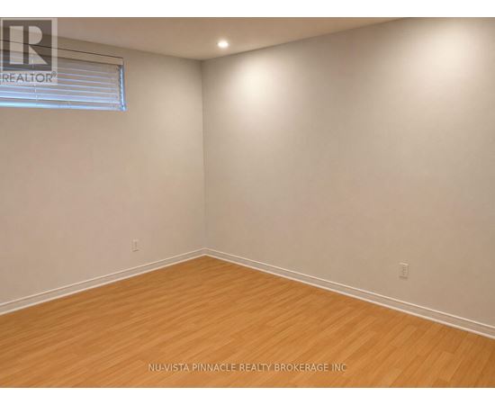 A room with wooden flooring and a window with blinds.