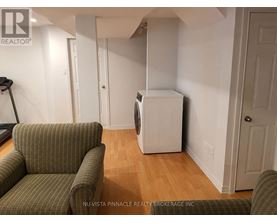 A room with a green couch and a white refrigerator.