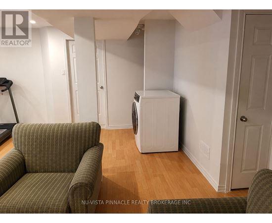 A room with a green couch and a white refrigerator.
