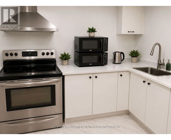 A modern kitchen with a stainless steel stove, black microwave, and white cabinets.