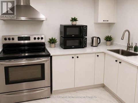 A modern kitchen with a stainless steel stove, black microwave, and white cabinets.