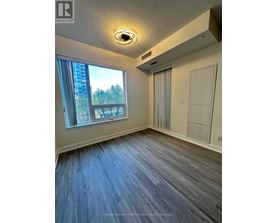 A room with a window overlooking a cityscape and a wooden floor.