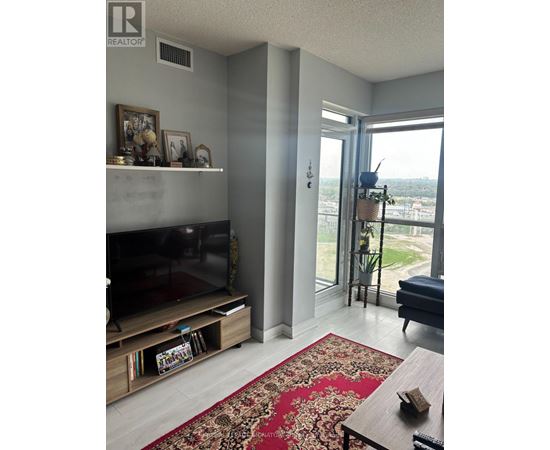 A living room with a flat screen TV and a large window.