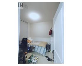 A small bedroom with a bed, a desk, and a chair.