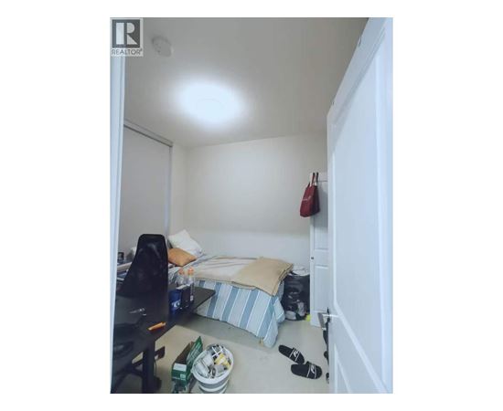 A small bedroom with a bed, a desk, and a chair.