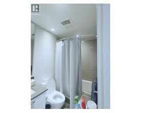 A white toilet in a small bathroom with a shower curtain.