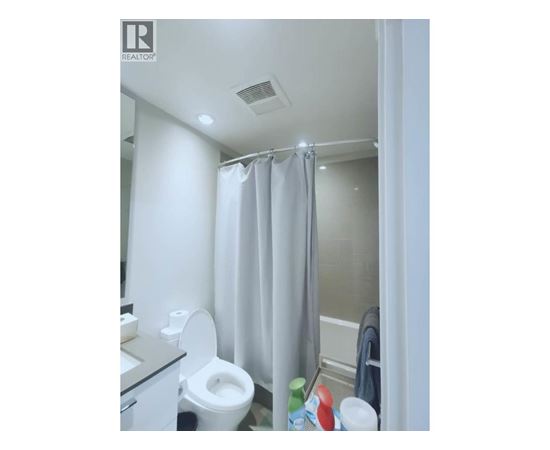 A white toilet in a small bathroom with a shower curtain.