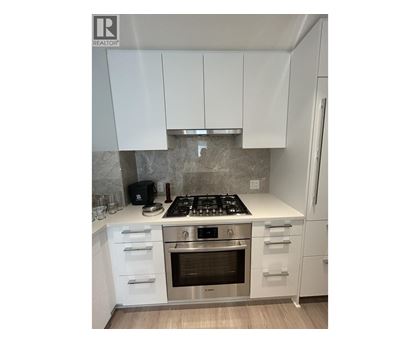 A modern kitchen with white cabinets and stainless steel appliances.