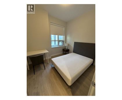 A bedroom with a bed, desk, and chair.