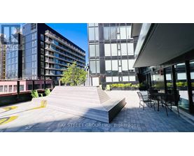 A modern outdoor seating area with a bench and chairs is surrounded by contemporary buildings.
