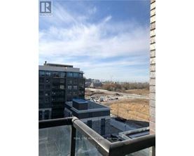 A view from a balcony overlooking a parking lot and a large building.