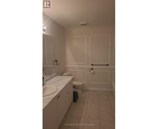 A white bathroom with a toilet, sink, and cabinetry.