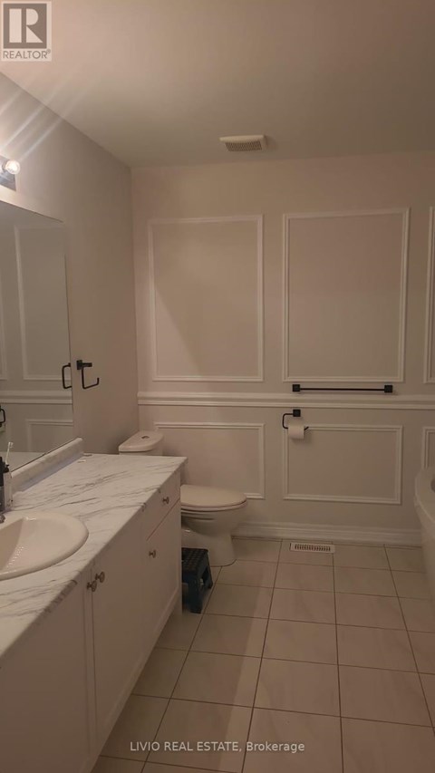 A white bathroom with a toilet, sink, and cabinetry.
