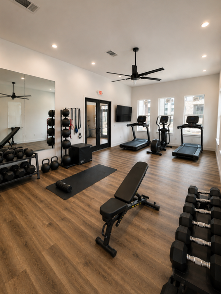 A gym with a variety of equipment including weights, benches, and treadmills.