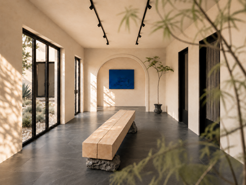 A long wooden bench sits in the middle of a room with a large screen on the wall.