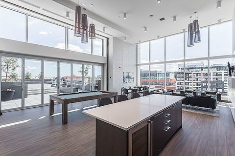 A modern office space with a long table and chairs, large windows, and pendant lights.