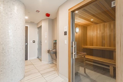 A bathroom with a wooden bench and a glass shower door.