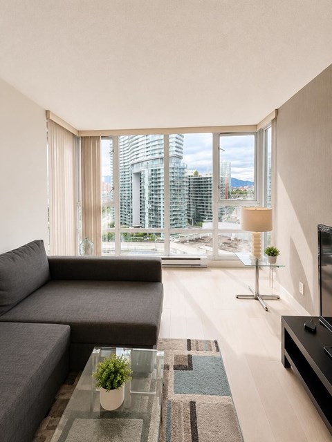 A modern living room with a grey sofa and a glass coffee table.