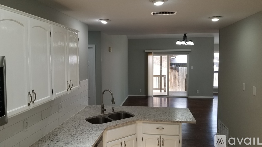 A kitchen with white cabinets and a granite countertop.