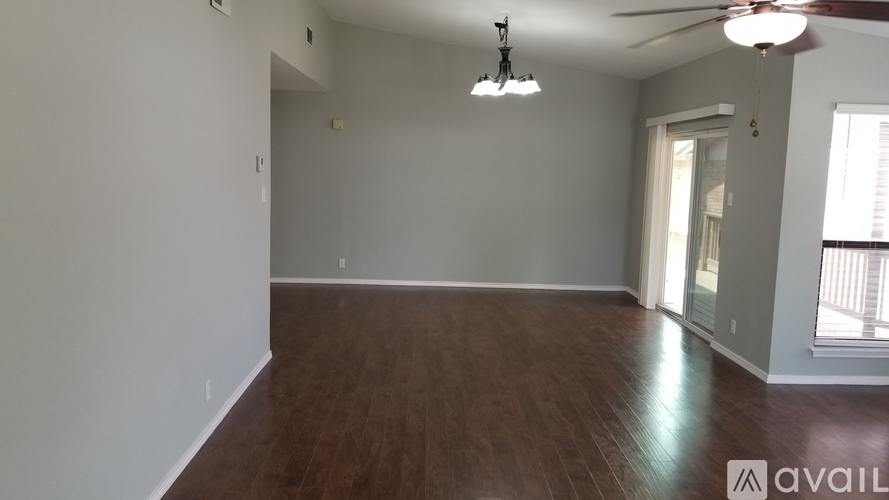 A spacious room with wooden flooring and a ceiling fan.