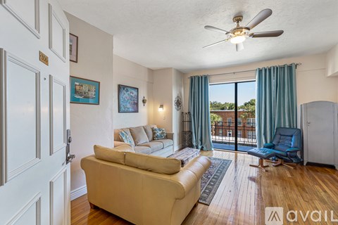A living room with a beige couch and a ceiling fan.