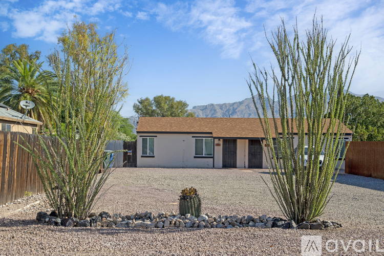 A house with a brown roof and a gravel driveway in front of it.