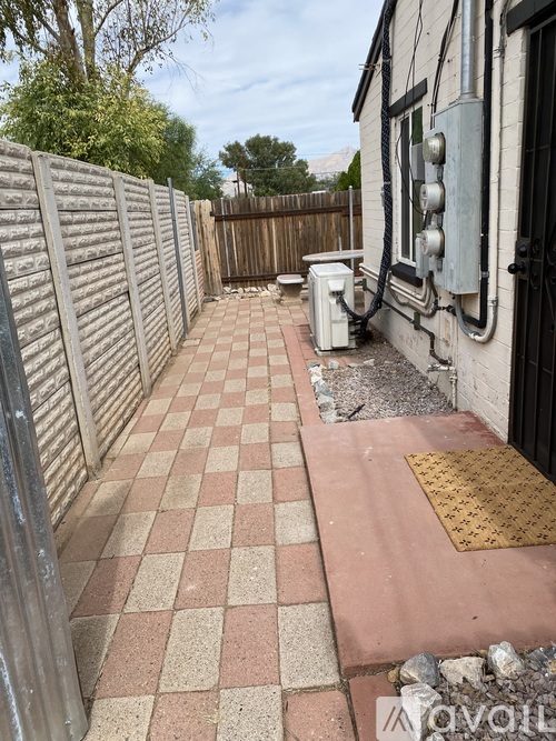 A backyard with a checkered tile walkway and a wooden fence.