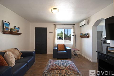 A living room with a blue couch and a rug on the floor.