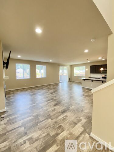 A spacious room with wooden flooring and a television on the wall.