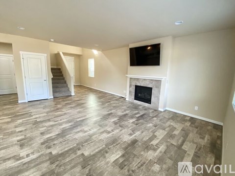 A spacious living room with a fireplace and a television mounted on the wall.