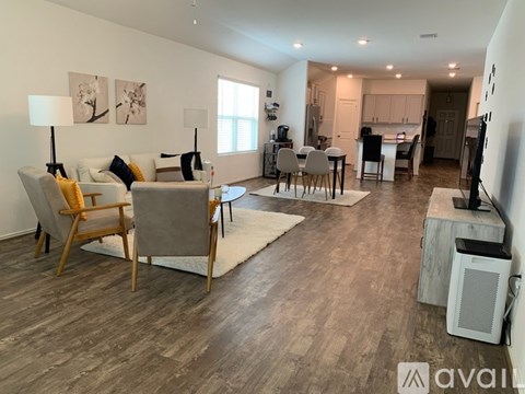 A living room with a grey couch and wooden chairs.