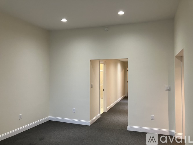 A spacious room with a carpeted floor and white walls.