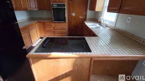 A kitchen with wooden cabinets and a black stove top.