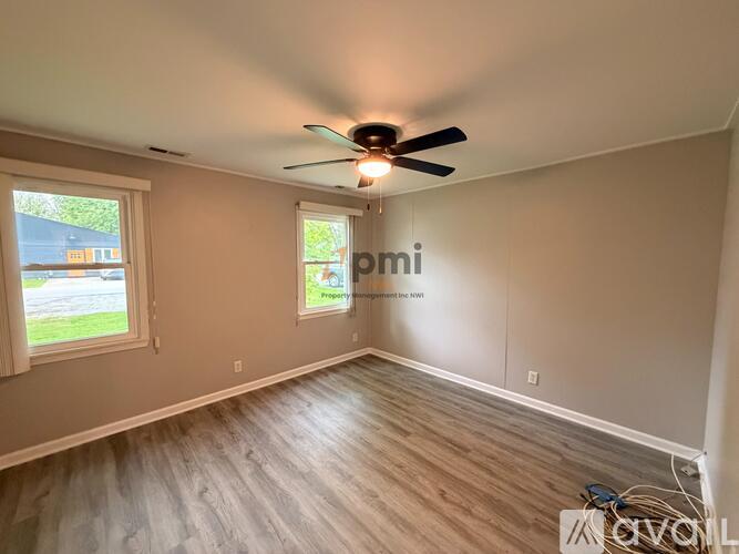 A room with a ceiling fan and wooden flooring.