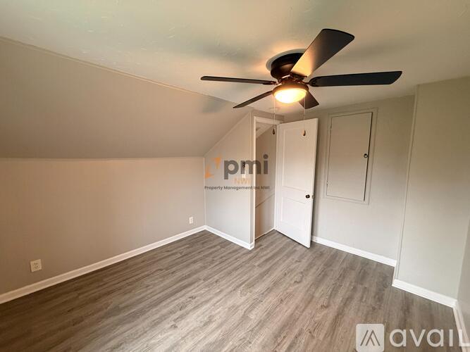 A room with a ceiling fan and light fixture, and a doorway leading to another room.