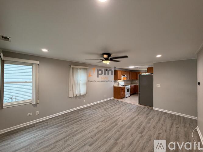 A spacious living room with a ceiling fan and hardwood flooring.