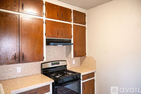 A kitchen with wooden cabinets and a black stove top oven.